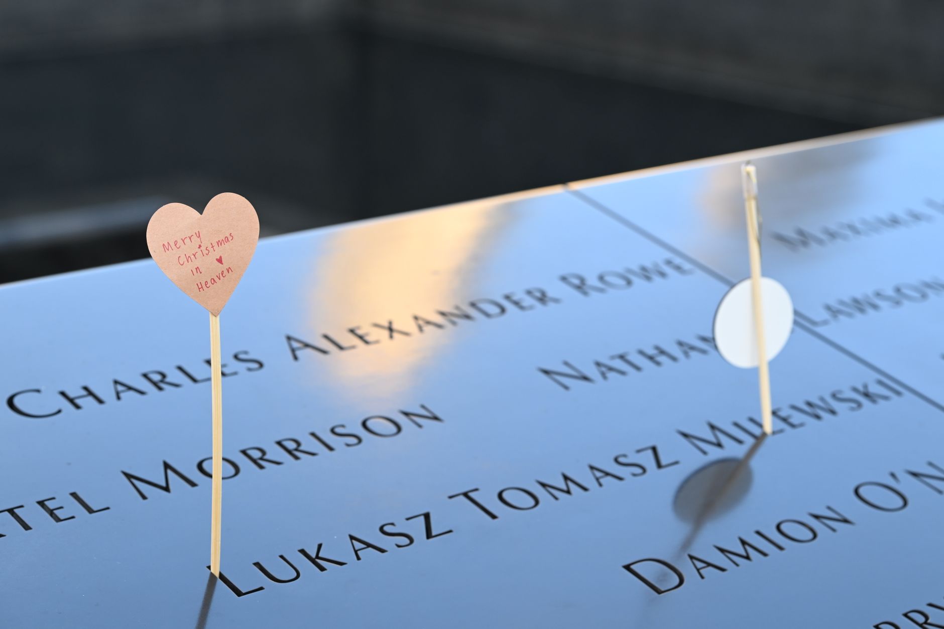 Emotional tribute with a heart card at a memorial displaying engraved names.